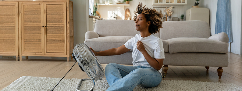 Woman sitting in front of fan for cooling