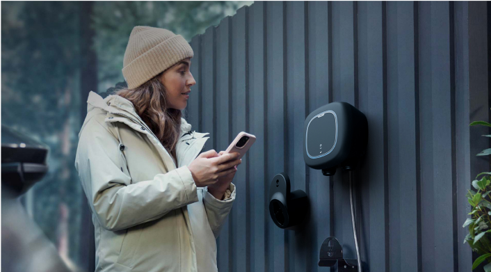 Woman checking her smart charger attached to her electric vehicle and mounted on the wall